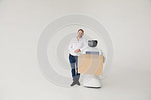 Modern Robotic Technologies. A man communicates with a robot, with cardboard box in hand.