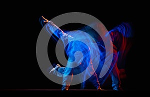 Stylish man dancing hip-hop in sportive style clothes isolated on dark background at dance hall in mixed neon light