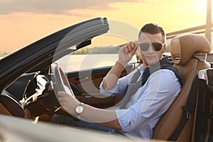 Stylish man driving modern luxury convertible car