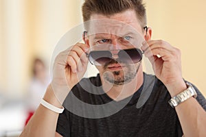 Stylish man holds sunglasses in his hands and looks to side