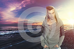 Stylish man with hooded sweatshirt the sea. Colorful sunset