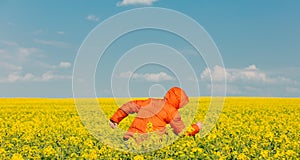 Stylish man in orange jacket in rapeseed field