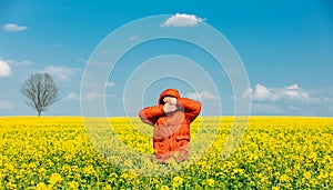 Stylish man in orange jacket in rapeseed field