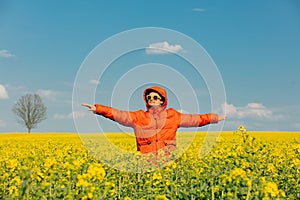 Stylish man in orange jacket in rapeseed field