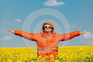 Stylish man in orange jacket in rapeseed field