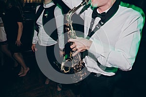 Stylish man playing on saxophone. hands on saxophone at wedding reception ceremony performing blues. live jazz music at party or