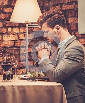 Stylish man pray before meal at restaurant.