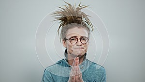 Stylish man praying in studio. Serious guy holding hands in prayer position