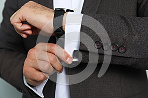 Stylish man putting on cufflink, closeup view