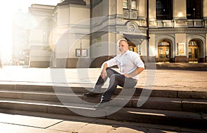 Stylish man relaxing on stone stairs at big classic building