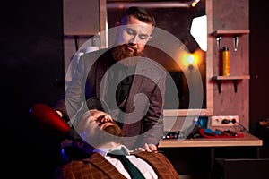 Stylish man sitting in barber shop while hairdresser dry his hair