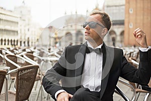 Stylish man sitting in cafe in tuxedo