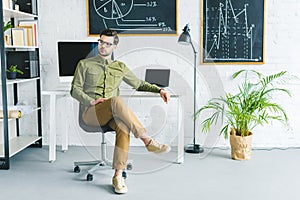 Stylish man sitting by table with computers