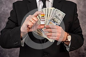 Stylish man with strong hands in a suit carries the vaccine in a jar and dollars for it.