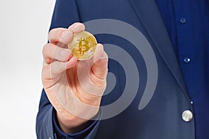 Stylish Man in suit holding gold bitcoin coin isolated on white background. Copy space and mock up. Selective focus and business