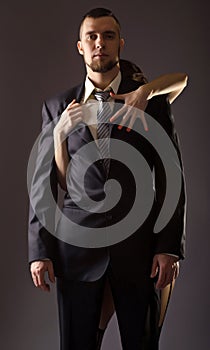 Stylish man in a suit and tie on gray background.