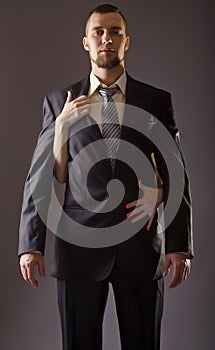 Stylish man in a suit and tie on gray background.