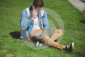 stylish man talking on smartphone and using laptop