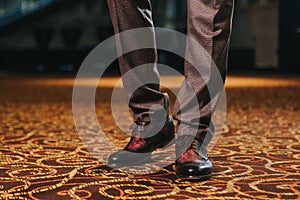 Stylish man in textured brown suit pants and brown and black brogue shoes