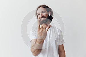 Stylish man in a white t-shirt with wireless headphones in his ears having fun listening to music smile on a white