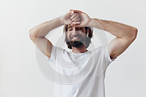 Stylish man in a white t-shirt with wireless headphones in his ears having fun listening to music smile on a white