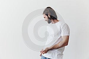 Stylish man in a white t-shirt with wireless headphones in his ears having fun listening to music smile on a white