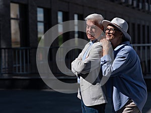 Stylish mature couple on a walk. Portrait of gray-haired man and woman hugging outdoors.