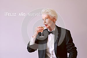 stylish mature senior woman in tuxedo with glass of sparkling wine celebrating