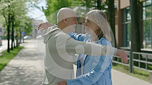 Stylish mature, sporty married elderly couple hugging and spending a leisure weekend outdoors. Mature family embracing