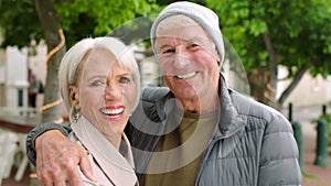 Stylish mature travelers in the city. Portrait of a happy senior couple embracing each other while standing outdoors
