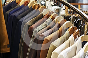 Stylish men`s jackets on hangers in the store, close-up