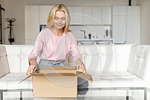 Stylish middle-aged blonde woman with carton box