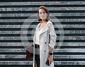 Stylish middle-aged female entrepreneur holding leather folder