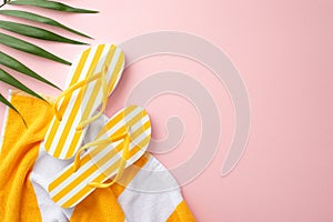 Stylish minimalistic beach vacation concept. Top view flat lay of yellow striped flip-flops, towel, green palm leaves on pastel