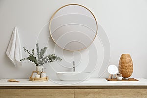 Stylish mirror, eucalyptus branches and vessel sink in modern bathroom. Interior design