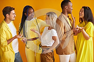 Stylish mixed race youth talking, smiling isolated on yellow background