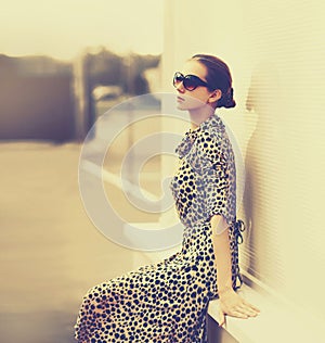 Stylish model woman posing in evening wearing dress with leopard print on city street