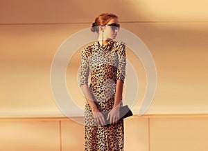 Stylish model woman posing in evening wearing dress with leopard print on city street