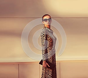Stylish model woman posing in evening wearing dress with leopard print on city street