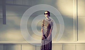 Stylish model woman posing in evening wearing dress with leopard print on city street