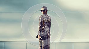 Stylish model woman posing in evening wearing dress with leopard print on city street