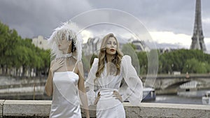 Stylish models in white dresses posing on the background of Paris streets and Effel tower. Action. Women in elegant