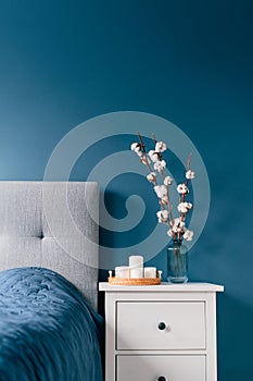 Stylish modern bedroom in dark colors. Cozy interior with navy blue walls, home decor. Bed with gray fabric headboard