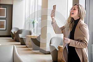 Stylish modern businesswoman entrepreneur in luxury office suite smiling and video chatting on smartphone