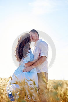 Stylish and modern couple kissing in a wheat field. A young woman hugs her boyfriend and kisses each other. The concept