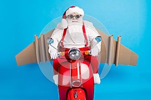 Stylish modern crazy white grey hair bearded santa claus with craft wings drive scooter x-mas christmas fast deliver