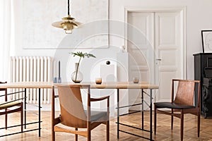 Stylish and modern dining room interior with design sharing table, chairs, gold pendant lamp, abstract paintings.