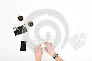 Stylish modern image workplace, hands typing on keyboard above  on white background. Phone, headphones, envelope