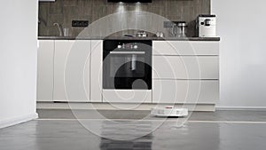 In a stylish modern kitchen is cleaning. The automatic robot vacuum cleaner moves along its trajectory. Elements of a