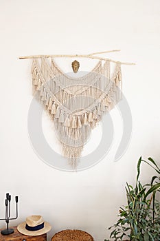 Stylish and modern living room interior in boho style with mockup photo frames, beige macrame and elegant accessories.